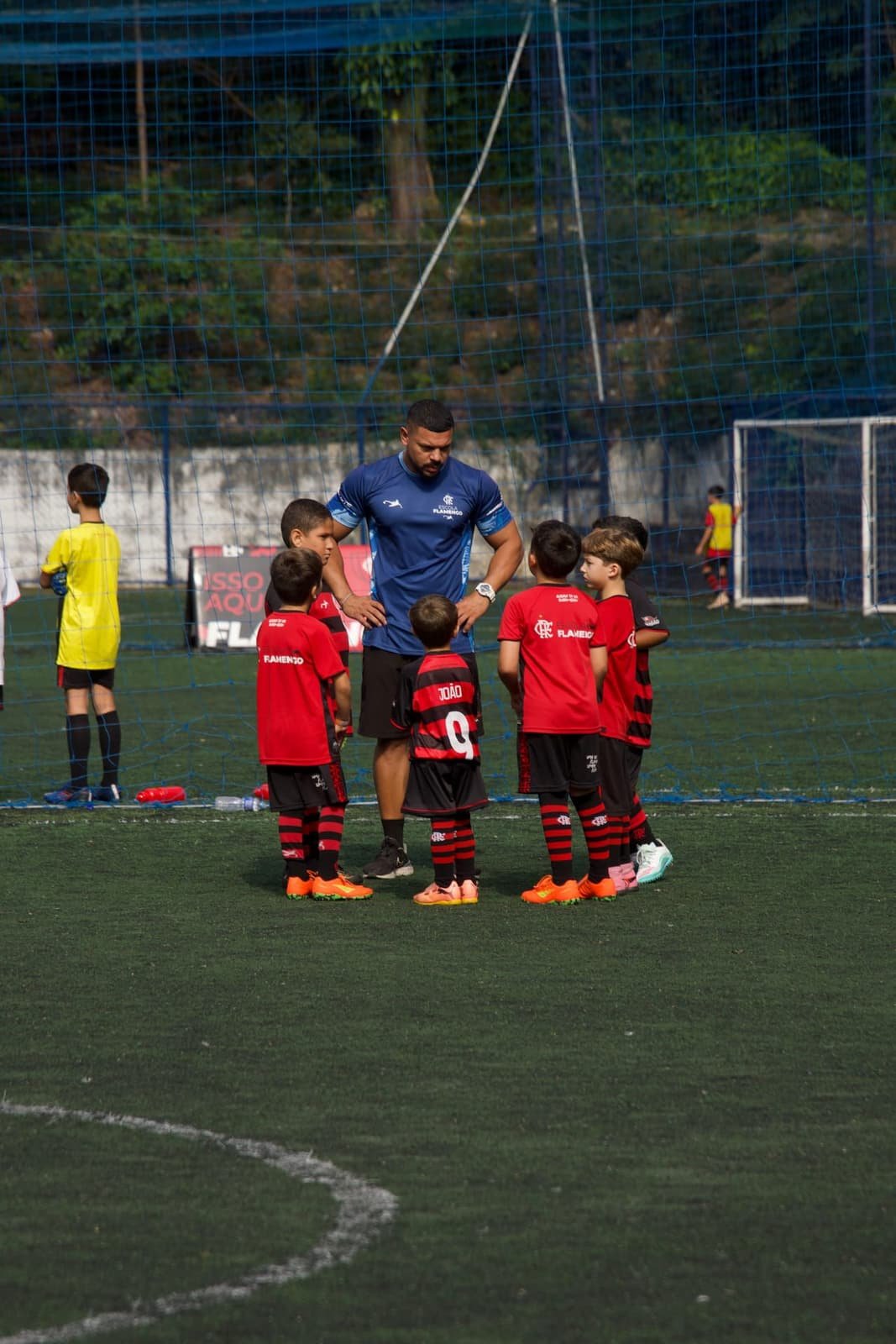 A coach briefing a group of players in kit on the sideline at a Copa Fla stage
