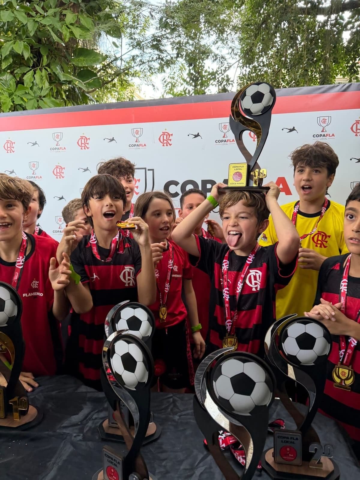 Players celebrating with trophies and medals on the Copa Fla podium